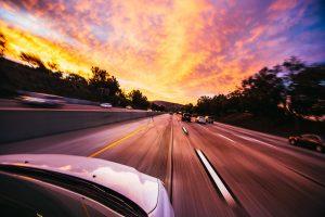 A car on the road during the sunset. 