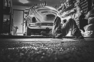 A man working on the car in a cluttered garage. Messiness is not a good thing when you need to pack your garage.